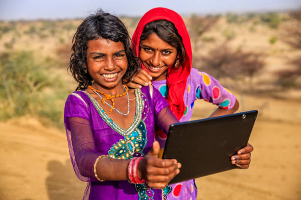 istock Happy Indian young girls using digital tablet, desert village, India 1127625317