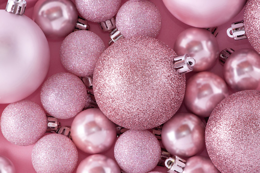 Pale pink composition on a New Year's theme. A small decorative Christmas balls for decoration on a pink background.