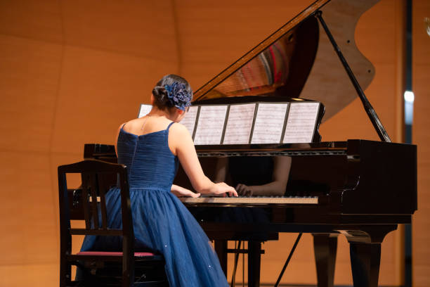 Teenage girl playing piano at concert hall Teenage girl playing piano at concert hall girl playing piano stock pictures, royalty-free photos & images