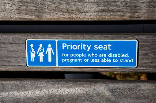 The Priority Seat sign asking for commuters to give up their seat for someone who is disabled, pregnant or less able to stand.  These signs can be seen on various forms of public transport in the UK.