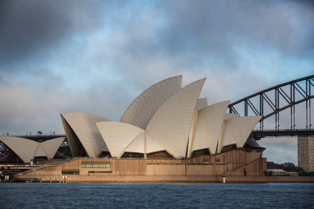 teatro dell'opera di sydney con nuvole drammatiche all'alba - sydney opera house sydney australia opera house bridge foto e immagini stock