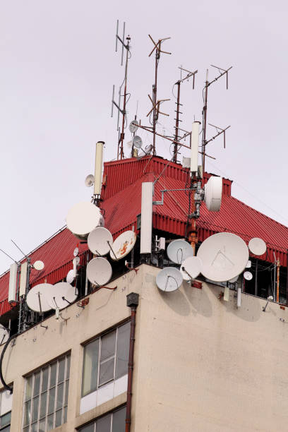 istock Telecommunication base stations network repeaters on the roof of building. The cellular communication aerial on city building roof. Cell phone telecommunication tower. Antennas on top of building. 1127633500