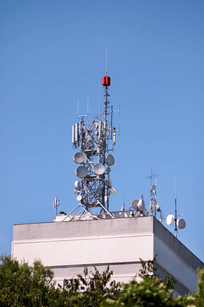 istock Telecommunication base stations network repeaters on the roof of building. The cellular communication aerial on city building roof. Cell phone telecommunication tower. Antennas on top of building. 1127634273