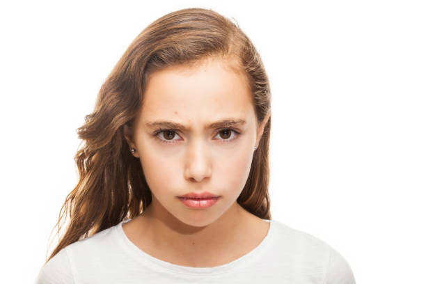 istock Grumpy young girl looking at the camera isolated on white background 1127635006