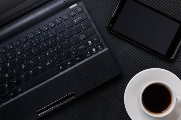 istock laptop with smartphone and cup of coffee on black textured surface. flat lay 1127635613
