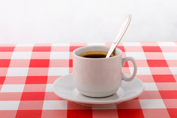 istock Cup of coffee on checkered tablecloth with white background 1127635818