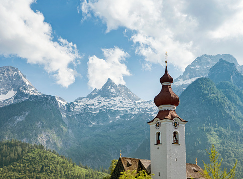A church steeple in Lofer, Austria, with the Loferer (Lofer) Mountains in the background.