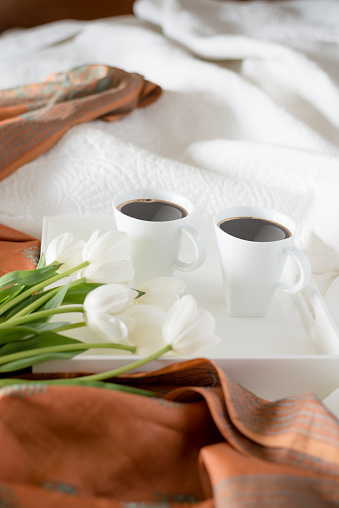 two cups of coffee on tray over empty bed