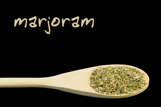 istock marjoram on wooden spoon isolated on black background 1127638562