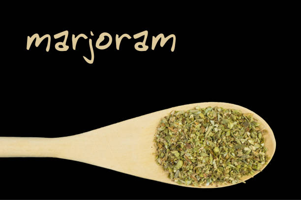 istock marjoram on wooden spoon isolated on black background 1127639167