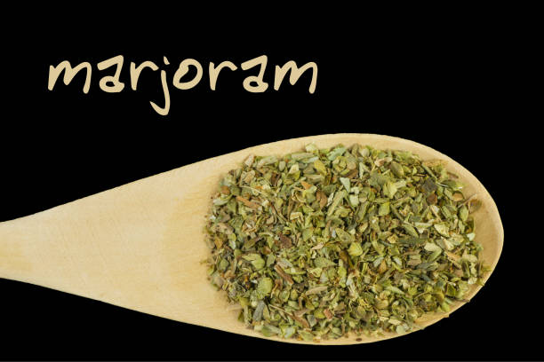 istock marjoram on wooden spoon isolated on black background 1127639618
