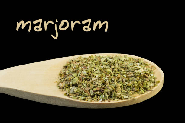 istock marjoram on wooden spoon isolated on black background 1127639663