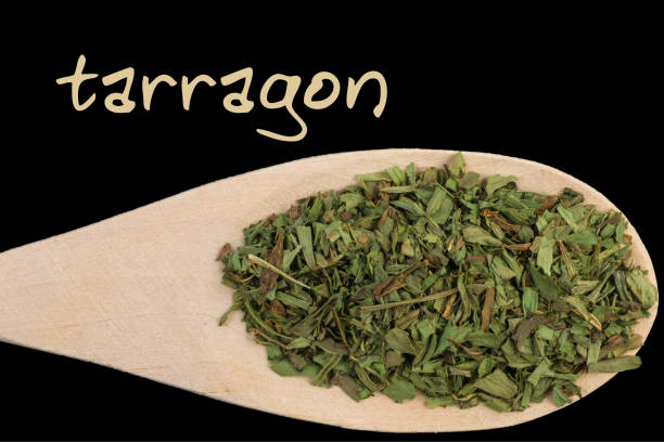 istock tarragon on wooden spoon isolated on black background 1127641860