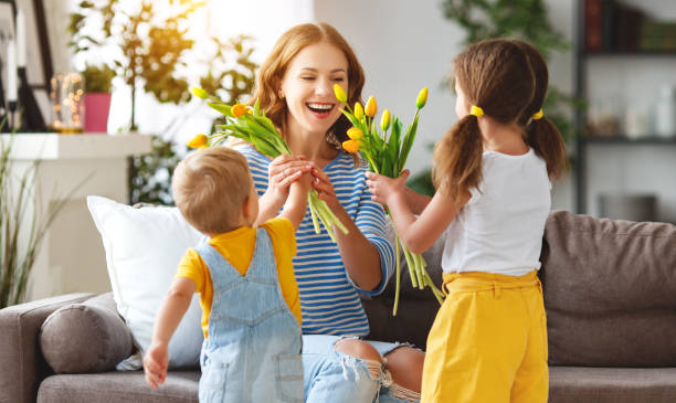 幸せな母の日!子供を祝福するママと彼女に贈り物を与えると花 - yellow tulip ストックフォトと画像