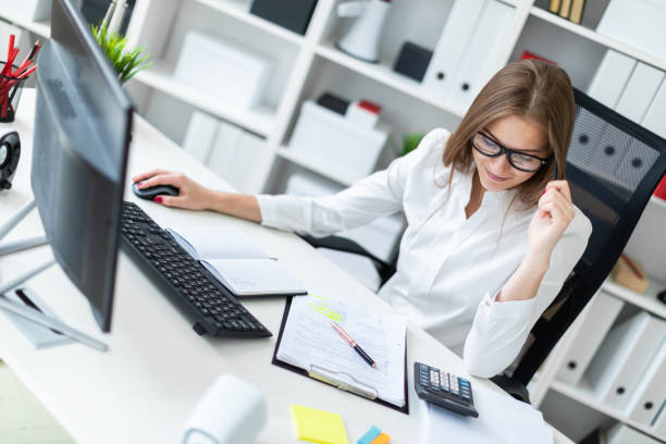 istock Young girl sitting at the table and working with a computer, documents and calculator 1127651465