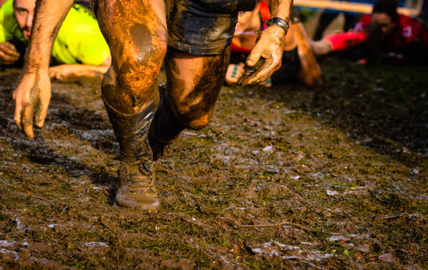 istock Mud race runners passing under a barbed wire obstacles during extreme obstacle race,detail of legs 1127657689