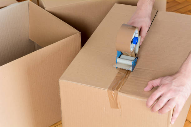 istock Man sealing a shipping cardboard box 1127660449