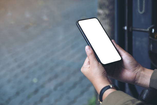 istock ands holding black mobile phone with blank white desktop screen 1127669172