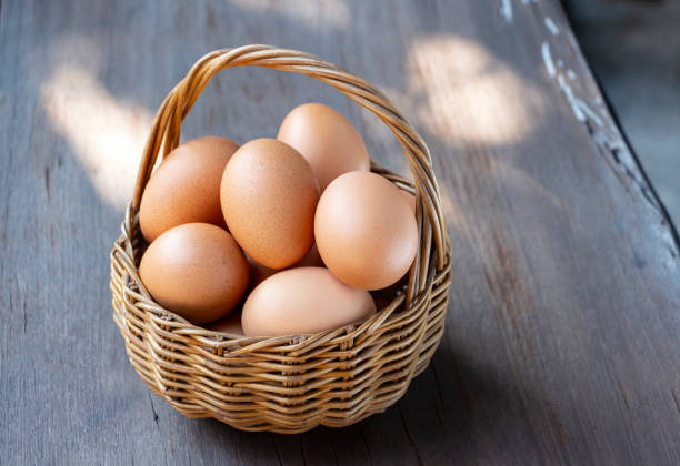Fresh eggs are in wicker baskets on a wood table. Eggs are nutritious foods on human health.