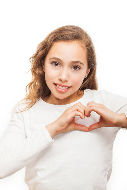 istock Young girl looking at camera showing heart gesture with two hands isolated on white background 1127669830
