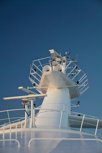 Radar and Communication Tower on a big tourist liner. Detail of navigation equipment, radar, and antennas on blue sky.