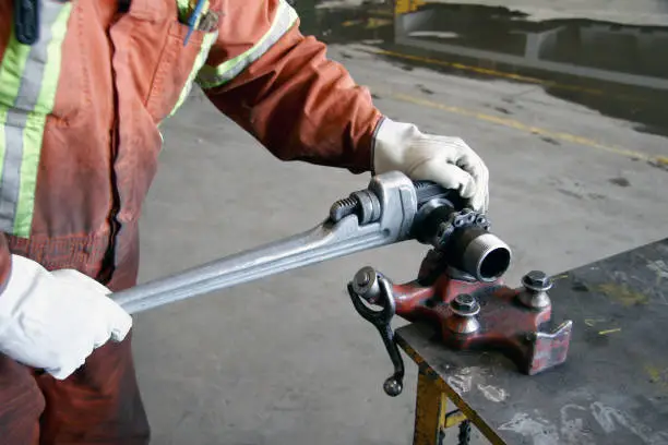 Technician using a wrench to tighten a fitting in heavy industry.
