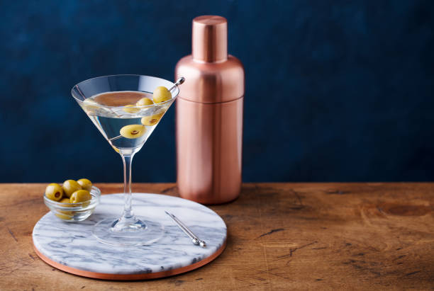 istock Martini cocktail with green olives, shaker on marble board, wooden table. Copy space. 1127684617