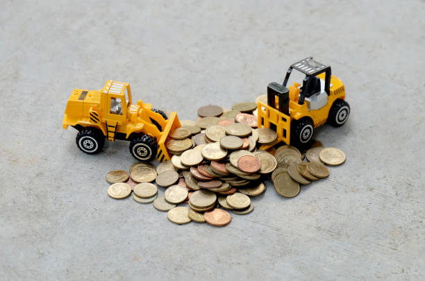 istock Truck model for construction with six gold coins on the cement floor,Construction industry business concept. 1127685521