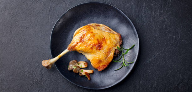istock Duck leg confit with mushroom sauce on black plate. Slate background. Top view. 1127687307