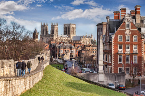 York City Walls, with a View to Minster 26 January 2015: York, North Yorkshire, England -  a view along the city wall towards York Minster, with tourists walking along the wall. york yorkshire stock pictures, royalty-free photos & images