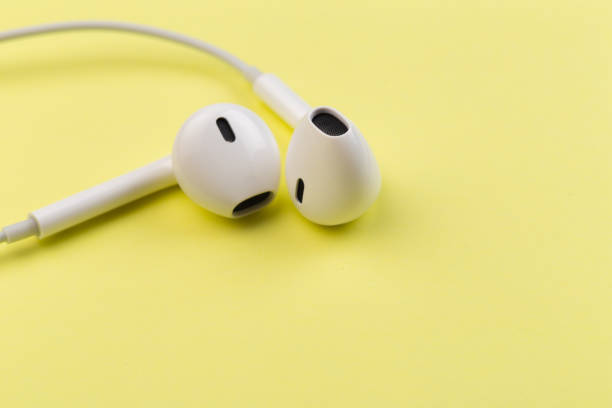 istock white earphones on yellow background 1127701755