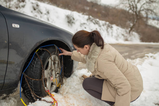 istock Beautiful woman installing snow chain on her car 1127702622