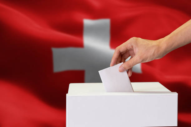 close-up of human hand casting and inserting a vote and choosing and making a decision what he wants in polling box with switzerland flag blended in background. - vote casting imagens e fotografias de stock