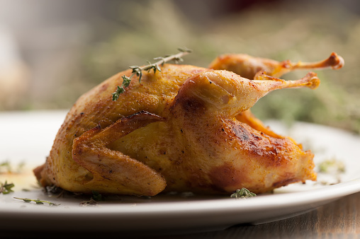 Roasted quail meat with rosemary. Delicious fried quail with herbs and greens. Photo taken on the workshop.