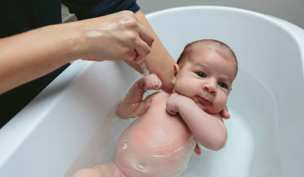 istock Newborn in the bathtub held by her mother 1127706355