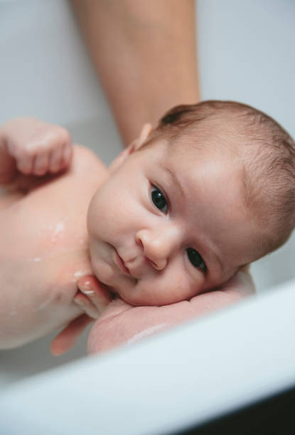 istock Newborn in the bathtub held by her mother 1127706376