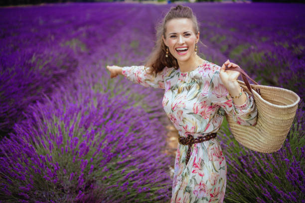 istock smiling elegant woman with straw bag pointing at something 1127707702