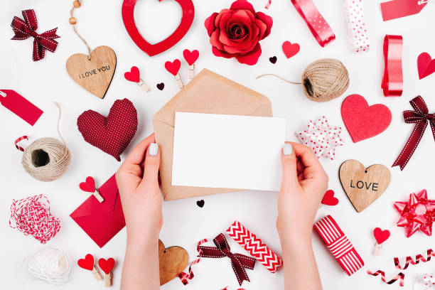 istock Female hands are holding a Blank white greeting card on white background with romantic decoration. flat lay 1127707786