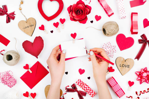 istock Female hands are holding a Blank white greeting card on white background with romantic decoration. flat lay 1127708187
