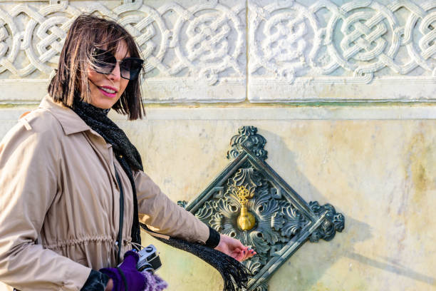 frau trinkt wasser aus einem alten wasser aus dem wasserhahn - istanbul people faucet turkey stock-fotos und bilder