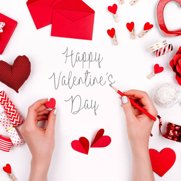 istock Women's hands holding valentine card on white background with romantic decoration. flat lay 1127709148