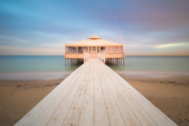White Romantic Pier on water with Real Rainbow, long exposure, sunset time
