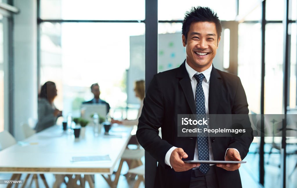 Putting his business online Cropped shot of a handsome young businessman using a tablet in the workplace Businessman Stock Photo