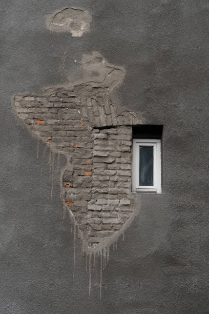 istock grunge old gray cement wall with small white window of building background 1127710940