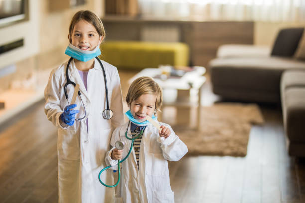istock Happy little kids pretending to be doctors while playing at home. 1127714136