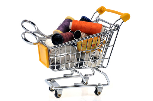 shopping cart filled with sewing material on a white background