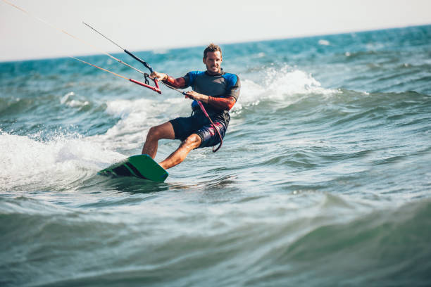 Athletic man riding on kite surf board Professional kiter makes the difficult trick on a beautiful background. Kitesurfing Kiteboarding action photos man among waves quickly goes kiteboarding stock pictures, royalty-free photos & images
