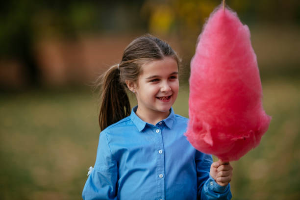 istock Happy girl eating a cotton candy at park 1127718676