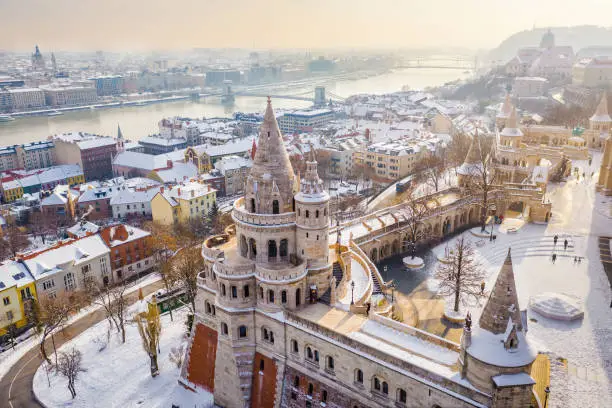 Budapest, Hungary - Aerial view of the snowy Fisherman's Bastion with Szechenyi Chain Bridge and St. Stephen's Basilica at background on a snowy winter morning
