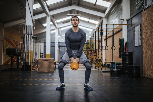 Man doing exercise with kettle bell in gym